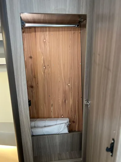 Y Knot Yacht Photos Pics 2021 Regal 36 Grande Coupe wooden closet interior with hanging rod and folded linens.