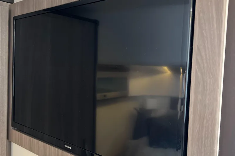 Y Knot Yacht Photos Pics Flat-screen TV in 2021 Regal 36 Grande Coupe interior, mounted on wood paneling.