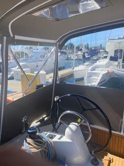 Pearl Yacht Photos Pics 2023 Jeanneau 380 yacht helm with marina view, showcasing steering wheel and nautical equipment.