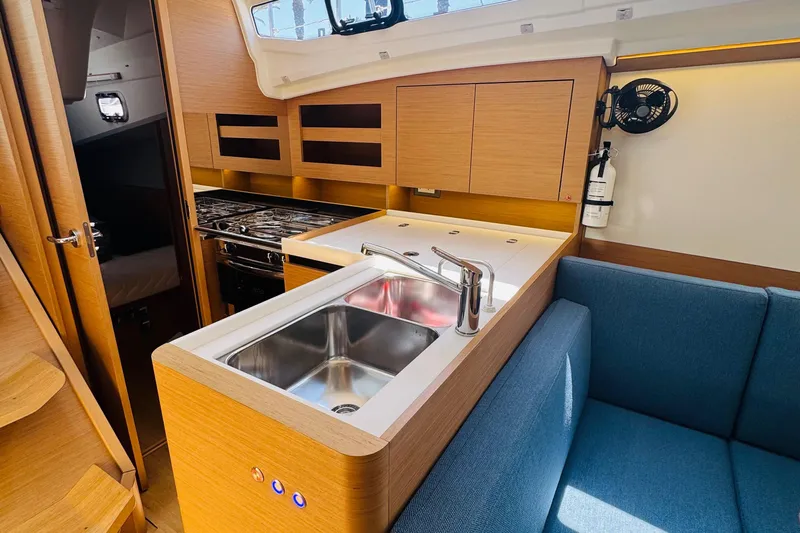 Pearl Yacht Photos Pics Modern kitchen interior of 2023 Jeanneau 380 yacht with sink, stove, and seating area.