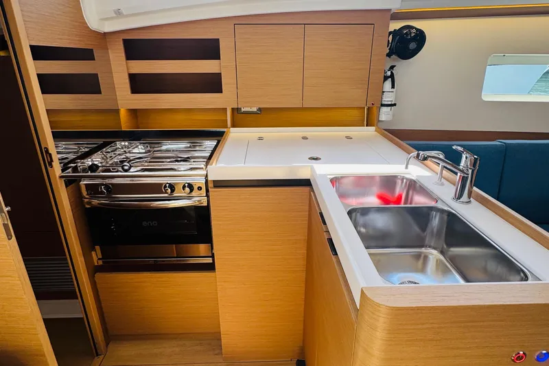 Pearl Yacht Photos Pics Modern kitchen in 2023 Jeanneau 380 yacht with stove, sink, and wooden cabinetry.