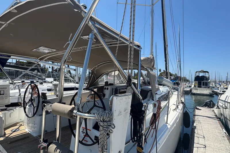 Pearl Yacht Photos Pics 2023 Jeanneau 380 sailboat docked at marina, featuring dual steering wheels and sunshade.