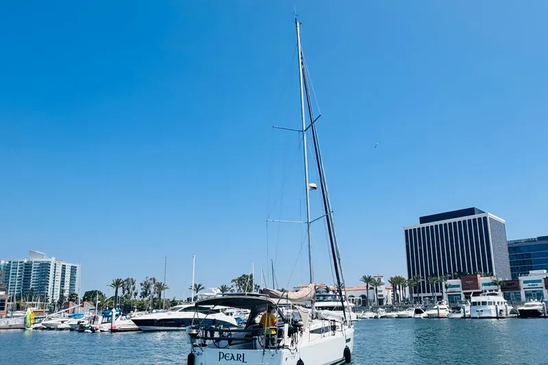 Pearl Yacht Photos Pics 2023 Jeanneau 380 sailboat docked in a marina with cityscape background.