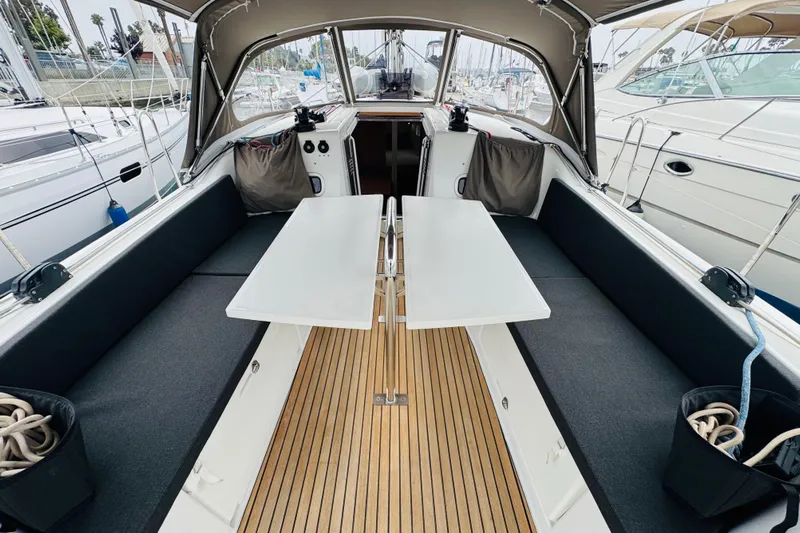 Pearl Yacht Photos Pics 2023 Jeanneau 380 yacht cockpit with seating, table, and canopy in marina setting.
