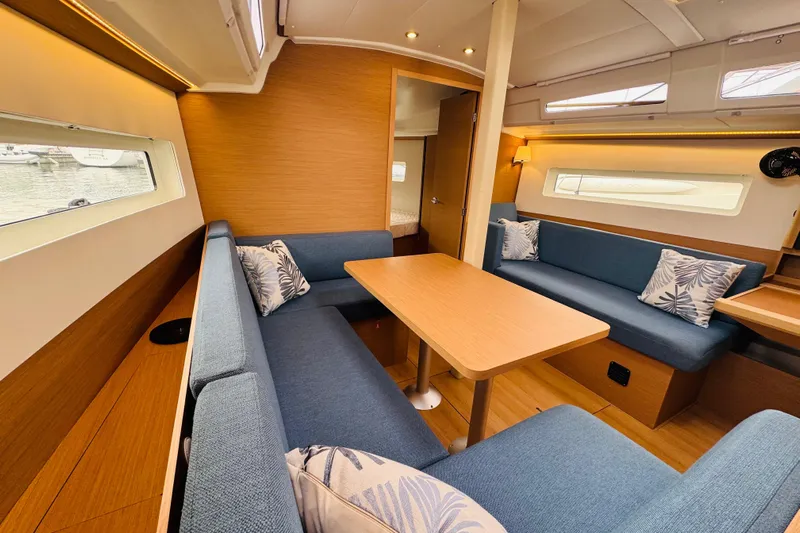 Pearl Yacht Photos Pics 2023 Jeanneau 380 yacht interior with blue seating and wooden table.