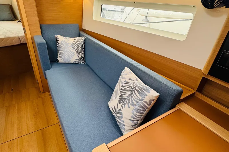Pearl Yacht Photos Pics Interior of 2023 Jeanneau 380 yacht with blue sofa and decorative pillows.