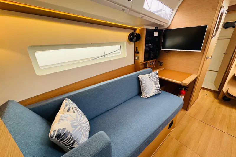 Pearl Yacht Photos Pics Modern Jeanneau 380 yacht interior with blue sofa, TV, and wooden accents, 2023 model.