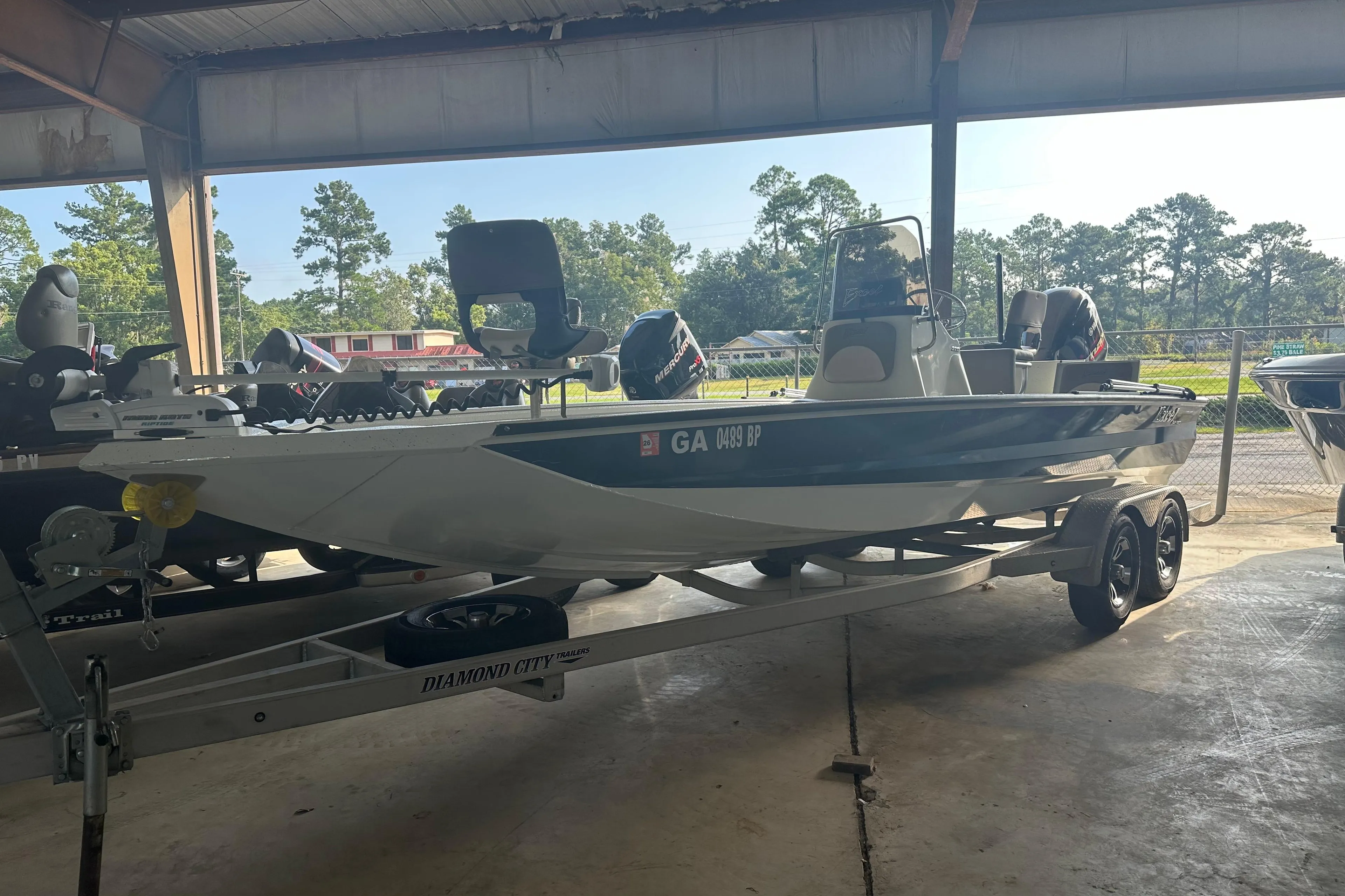2018 Excel 220 Bay Pro boat on trailer in covered storage area.