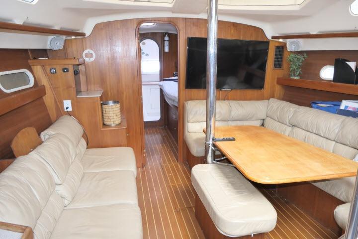 Interior of 1999 Hunter 450 Passage yacht with wood paneling and beige seating.