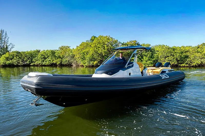  Yacht Photos Pics 2025 SACS Strider 11 boat cruising on a sunny day near lush greenery.
