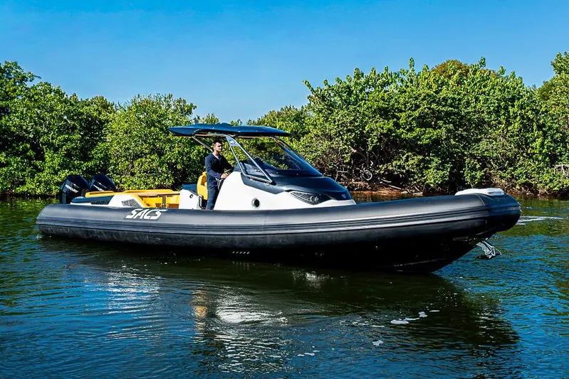  Yacht Photos Pics 2025 SACS Strider 11 boat cruising on a sunny day near lush greenery.