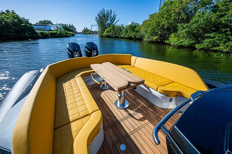  Yacht Photos Pics Luxurious 2025 SACS Strider 11 boat with yellow seating and wooden deck on a scenic waterway.