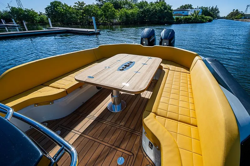 Yacht Photos Pics 2025 SACS Strider 11 boat with yellow seating and wooden deck, docked by the water.