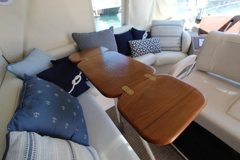  Yacht Photos Pics Interior of 2000 Bayliner 4788 Pilothouse Motoryacht with wooden table and cushioned seating.