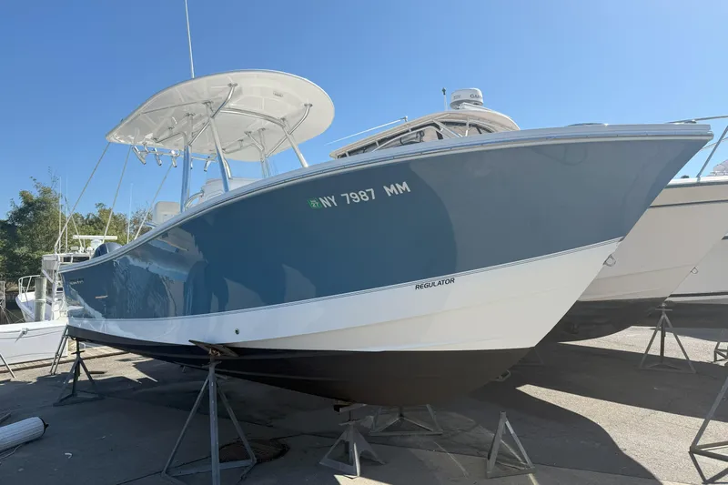  Yacht Photos Pics 2017 Regulator 25 boat on stands, blue hull, sunny day.