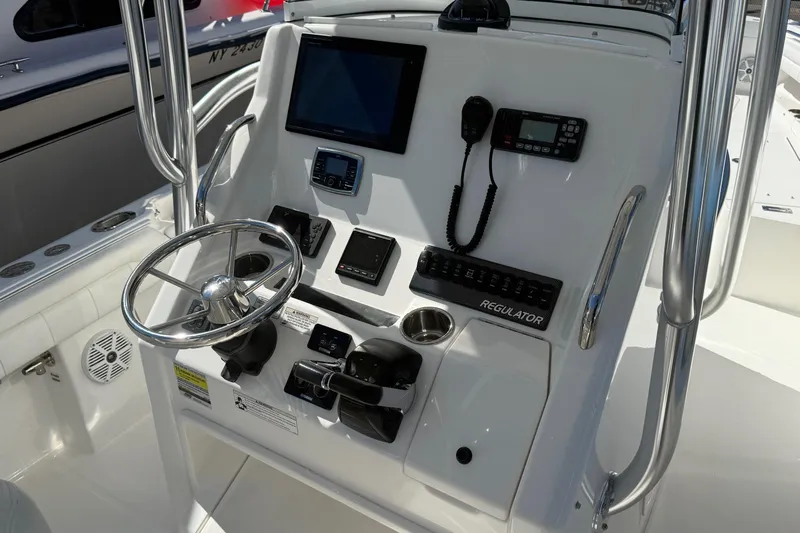  Yacht Photos Pics Control panel of a 2017 Regulator 25 boat with steering wheel and navigation equipment.