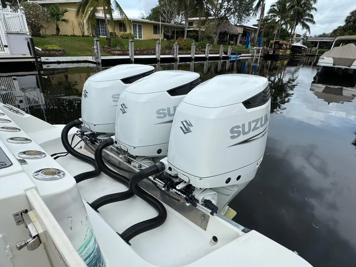 Yacht Photos Pics Triple Suzuki outboard engines on a 2010 Hydra-Sports 3500 VX boat docked by a canal.