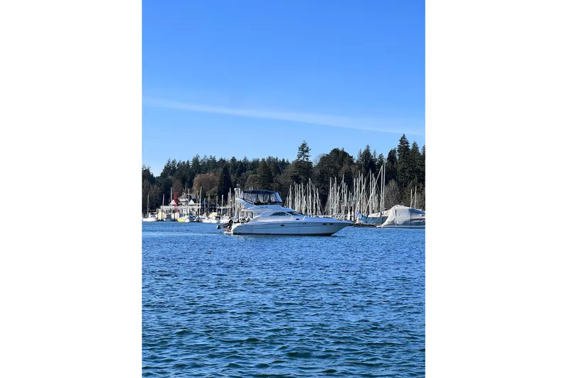 Rising Tide Yacht Photos Pics 1996 Sea Ray 400 Sedan Bridge yacht on calm water near marina.