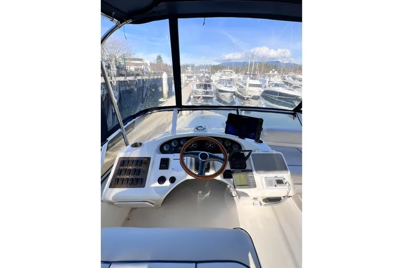 Rising Tide Yacht Photos Pics 1996 Sea Ray 400 Sedan Bridge helm with marina view, featuring navigation equipment.