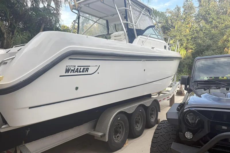  Yacht Photos Pics 2002 Boston Whaler 285 Conquest boat on trailer beside a black vehicle.