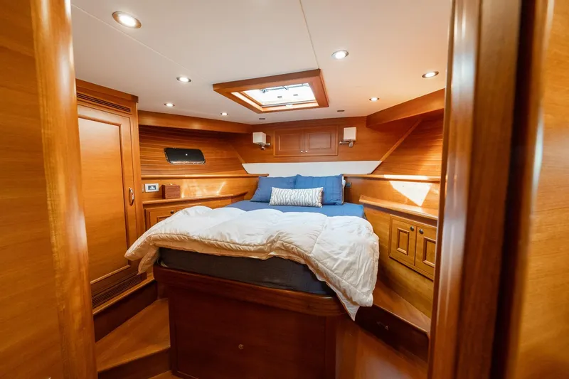 Dash Yacht Photos Pics Luxurious cabin interior of 2016 Grand Banks 72 Aleutian RP yacht, featuring wood paneling and cozy bedding.