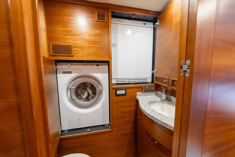Dash Yacht Photos Pics Laundry area with washer, dryer, and sink in 2016 Grand Banks 72 Aleutian RP yacht.