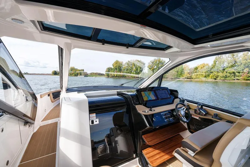 Yacht Photos Pics 2023 Sea Ray Sundancer 370 Outboard cockpit with modern controls, overlooking serene water and trees.