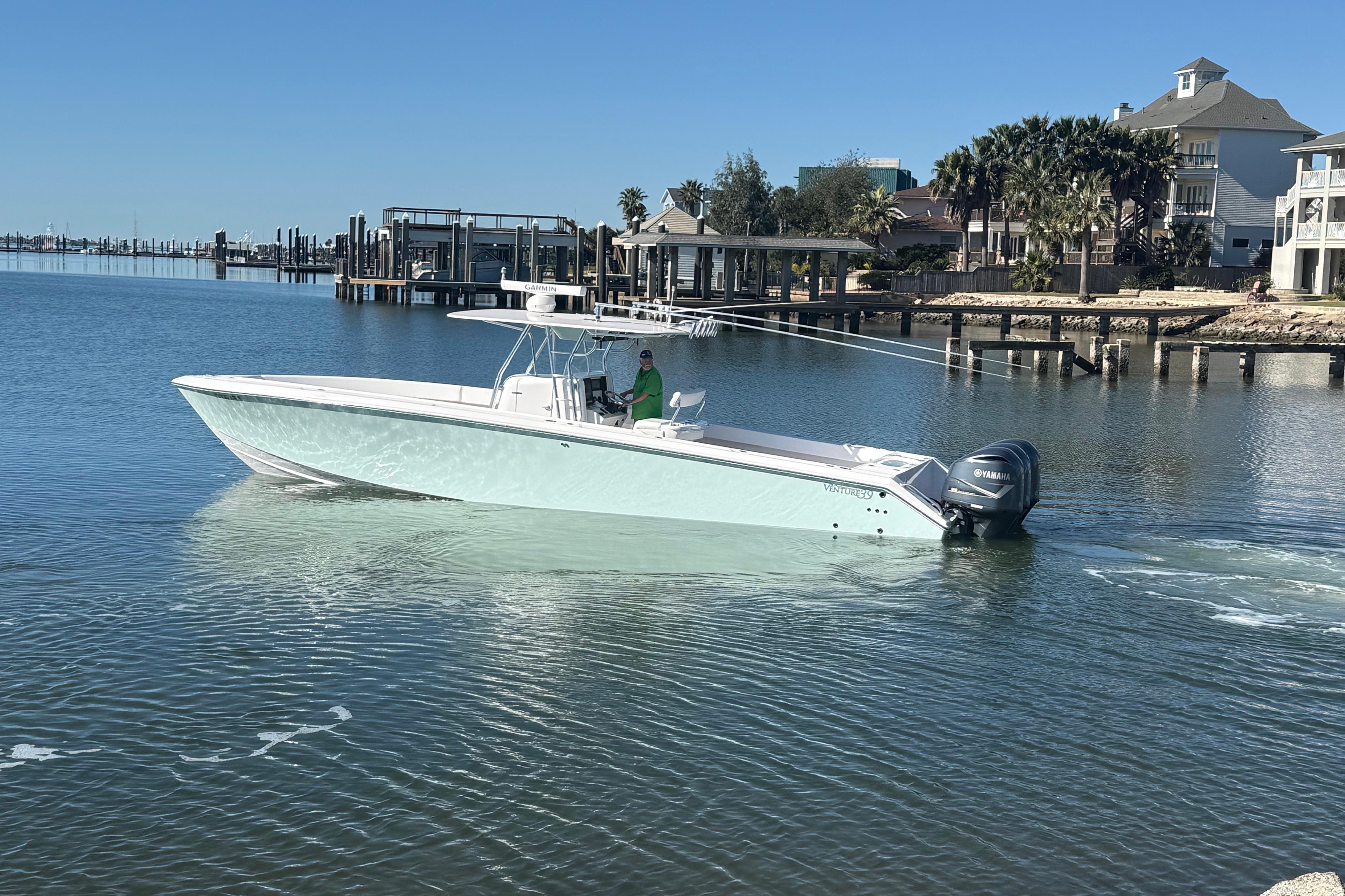 2009 Venture 39 Open boat cruising near a marina with waterfront homes.