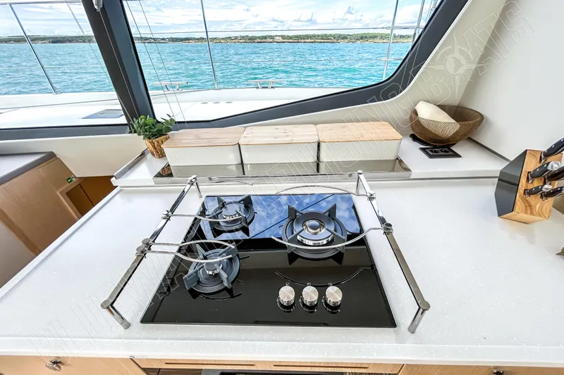 Fun Pass Yacht Photos Pics Modern yacht kitchen with stove, cutting boards, and ocean view on Privilege 580, 2025 model.