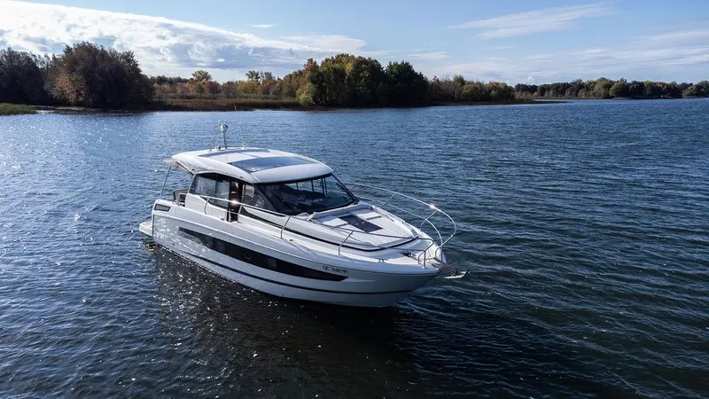  Yacht Photos Pics 2021 Jeanneau NC 37 boat cruising on a serene lake with lush trees in the background.