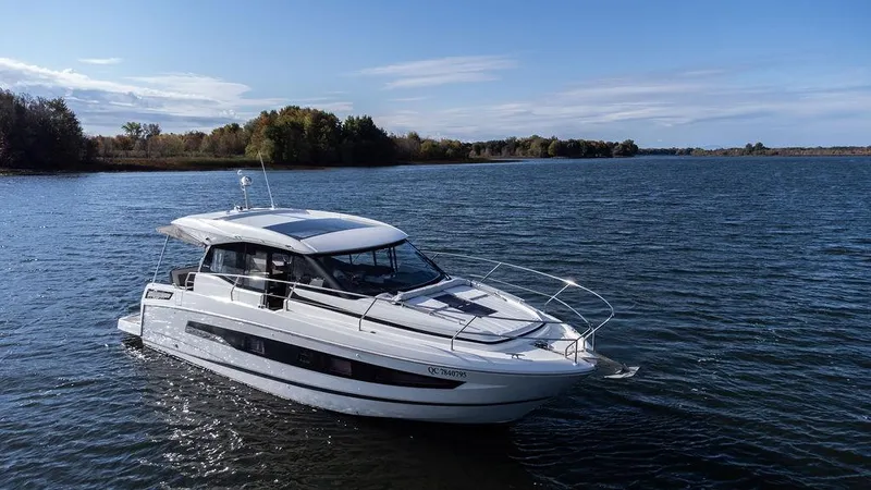  Yacht Photos Pics 2021 Jeanneau NC 37 boat cruising on a serene lake under a clear blue sky.