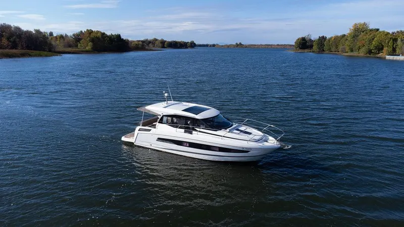  Yacht Photos Pics 2021 Jeanneau NC 37 yacht cruising on a serene river with lush green banks.