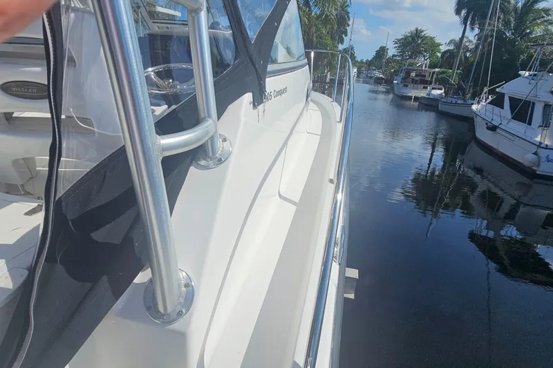  Yacht Photos Pics 2005 Boston Whaler 305 Conquest docked on a calm, sunny waterfront.
