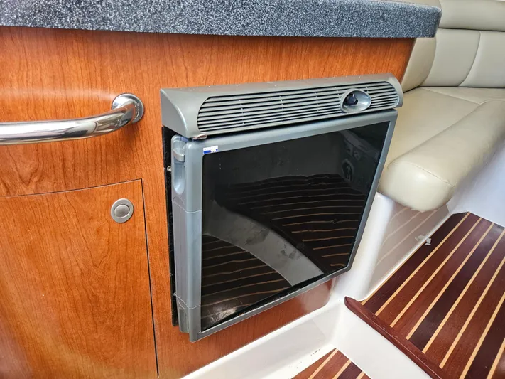  Yacht Photos Pics 2005 Boston Whaler 305 Conquest interior with compact fridge and wooden cabinetry.