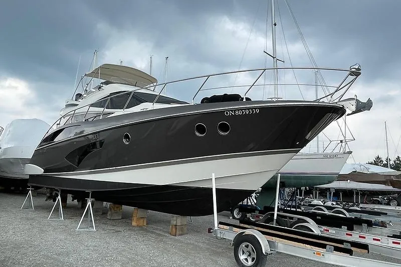  Yacht Photos Pics 2012 Marquis 500 Sport Bridge yacht on dry dock under cloudy sky.