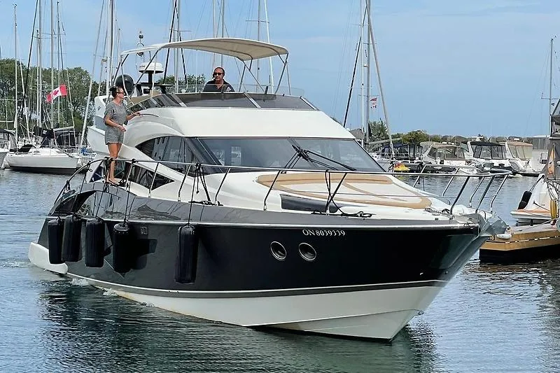  Yacht Photos Pics 2012 Marquis 500 Sport Bridge yacht cruising in a marina, with people on deck.