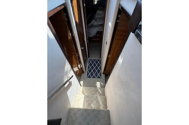  Yacht Photos Pics Interior staircase of 2012 Marquis 500 Sport Bridge yacht, featuring carpeted steps and wooden doors.