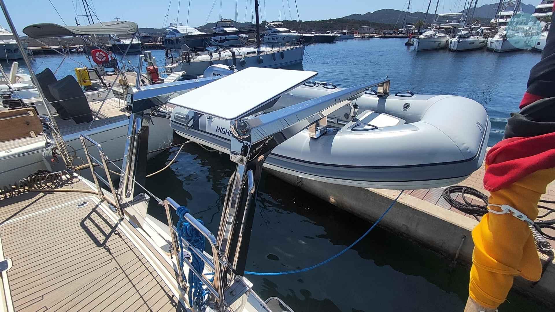 Sailboat Amel 55 (2017) with dinghy at marina, sunny day, clear water.