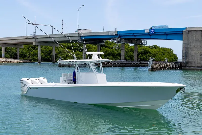  Yacht Photos Pics 2023 Contender 39 ST boat on water near a bridge, featuring triple outboard engines.