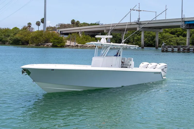  Yacht Photos Pics 2023 Contender 39 ST boat cruising on a calm waterway near a bridge.