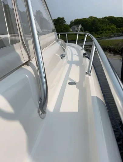  Yacht Photos Pics 2002 Intrepid 348 WA boat deck with stainless steel railings, docked near lush greenery.