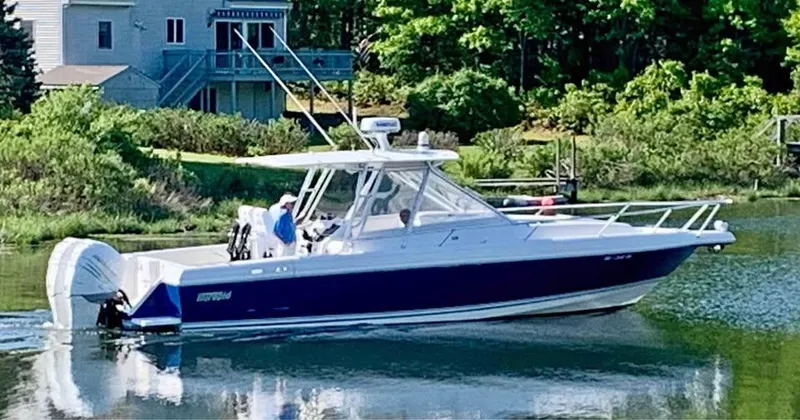 Yacht Photos Pics 2002 Intrepid 348 WA boat cruising on a calm lake near a house and lush greenery.