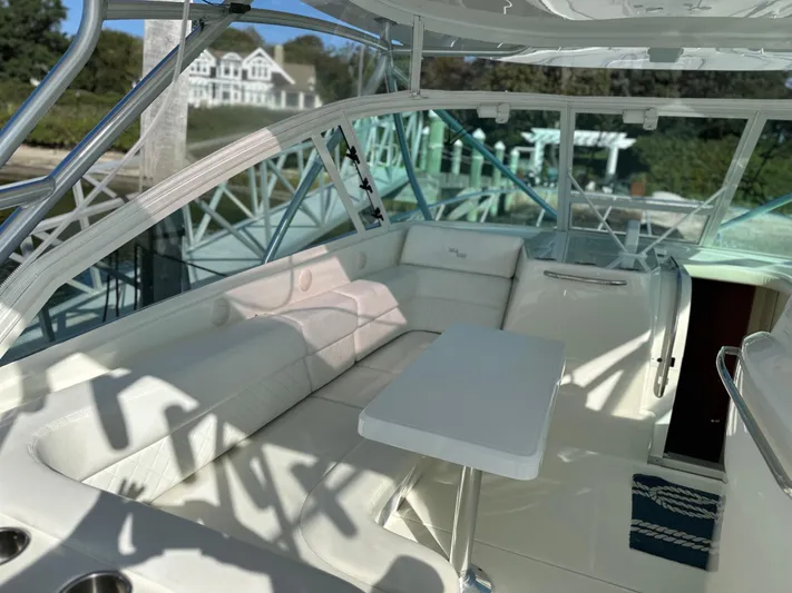 Still Wreckless Yacht Photos Pics 2014 SeaVee 430 SE boat interior with white seating and table, docked near a house.