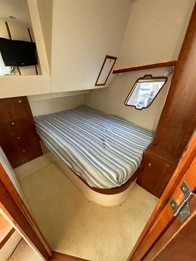 Still Wreckless Yacht Photos Pics 2014 SeaVee 430 SE cabin with bed, striped bedding, and wooden cabinetry.