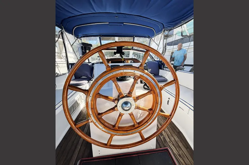 Makani Yacht Photos Pics Wooden helm of 1993 Gozzard 44 MK1 AC sailboat, featuring blue canopy and seating.