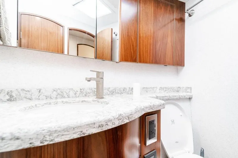 Trailer Trash Yacht Photos Pics Luxurious bathroom in 2021 Viking 58 Convertible yacht with marble countertop and wooden cabinets.