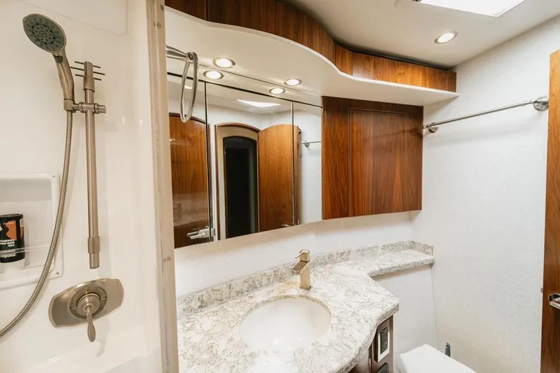 Trailer Trash Yacht Photos Pics Luxurious bathroom in 2021 Viking 58 Convertible yacht with marble countertop and wooden cabinetry.