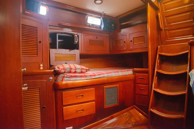Tuatara Yacht Photos Pics Cozy wooden cabin interior of 1983 Little Harbor 63 yacht with bed and storage.