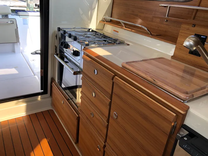  Yacht Photos Pics 2022 Ranger Tugs R-27 interior kitchen with stove, wooden cabinets, and cutting board.