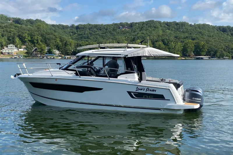  Yacht Photos Pics 2024 Jeanneau NC 895 boat on a serene lake with lush green hills.